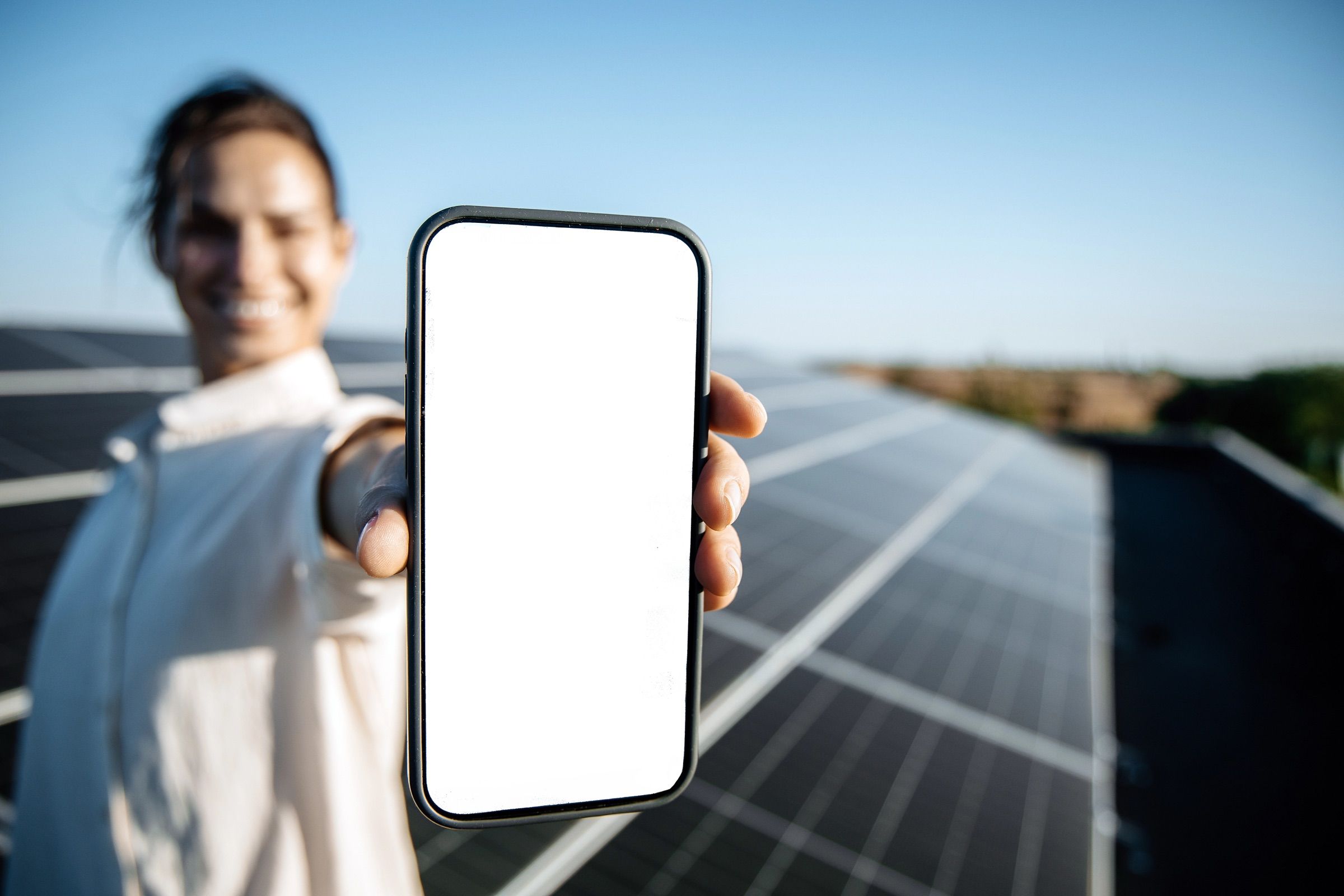 Femeie care arată telefonul în fața panourilor fotovoltaice